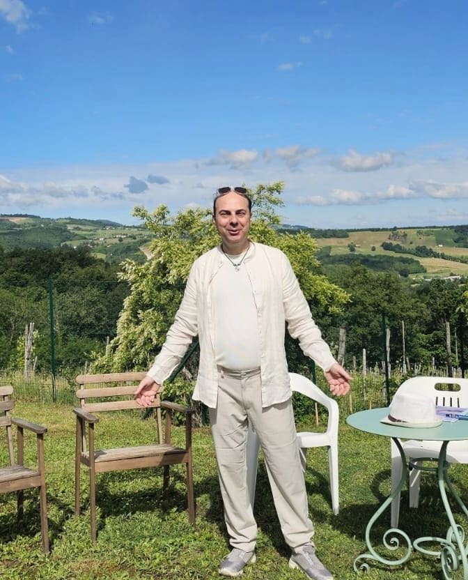 Andrea Barani, vestito di chiaro, sulle colline piacentine sotto un cielo aperto.