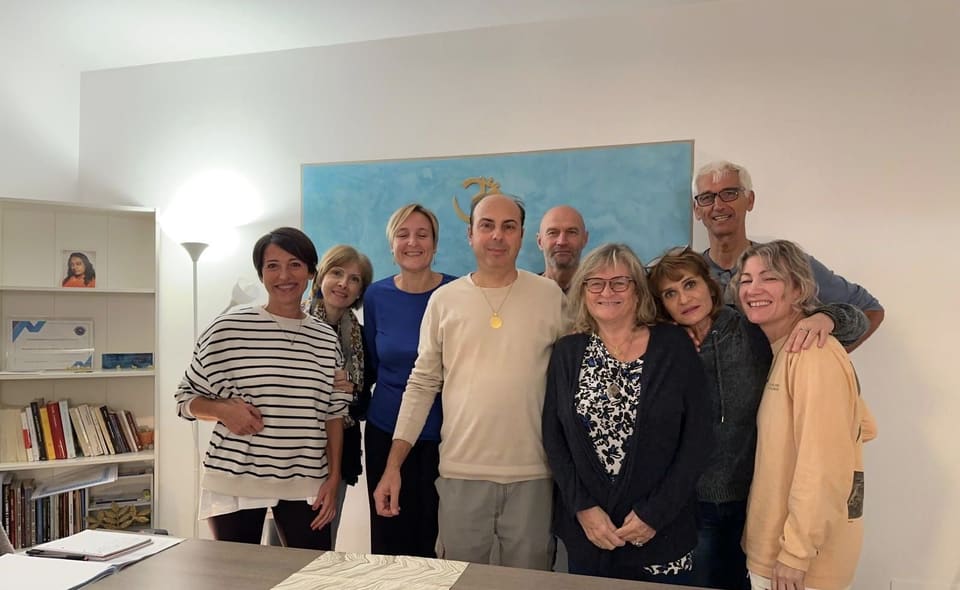 Un gruppo numeroso con Andrea Barani nella sala delle lezioni, davanti al dipinto con il simbolo Om.