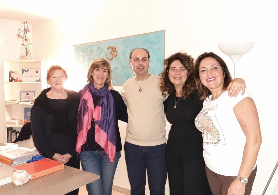 Andrea Barani con quattro partecipanti nella sala delle lezioni, davanti al dipinto con il simbolo Om.