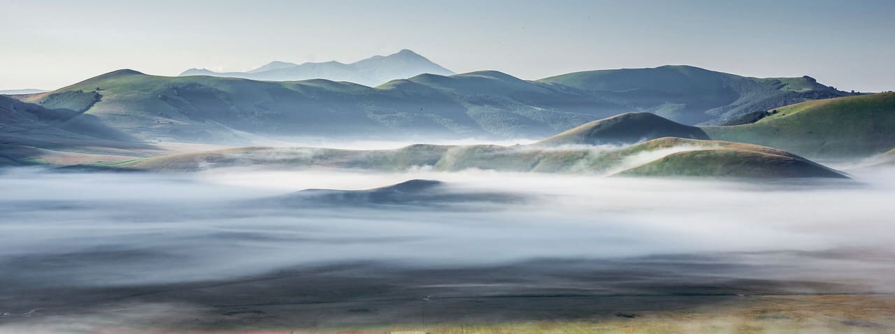 Colline all’alba, con banchi di nebbia che riposano nella valle.